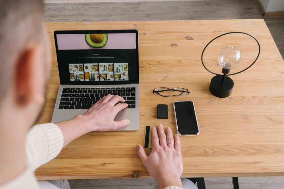 Webentwickler arbeitet in einem hellen Büro am Laptop, Blick über die Schulter