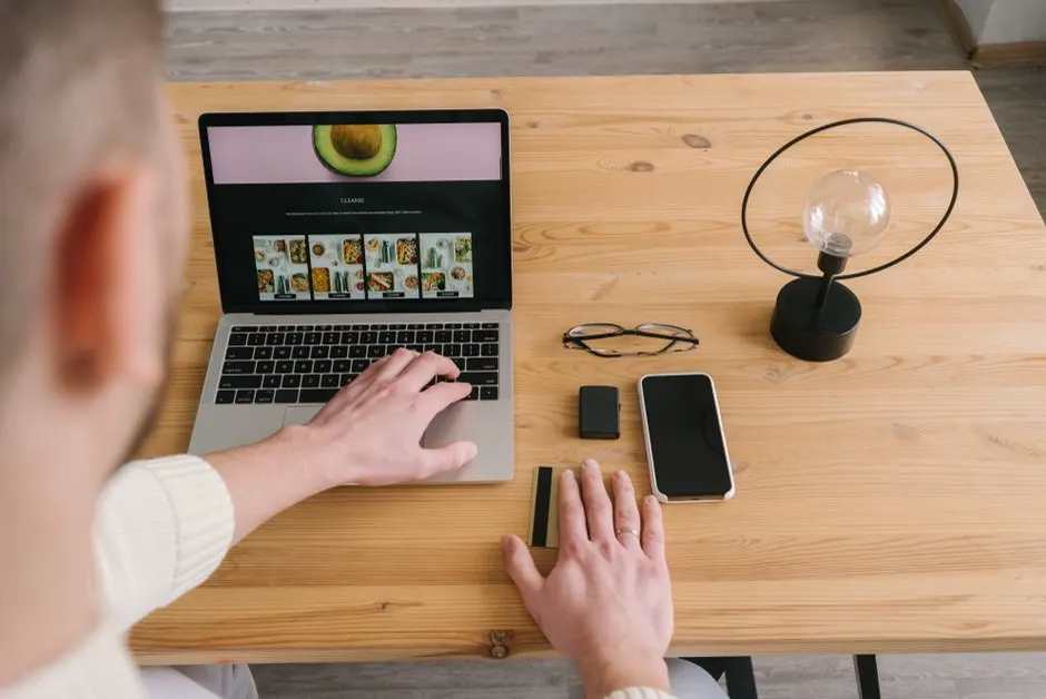 Webentwickler arbeitet in einem hellen Büro am Laptop, Blick über die Schulter